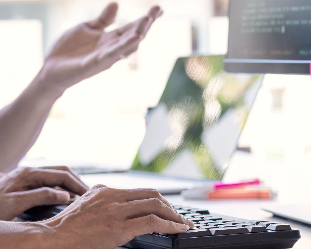 Zwei Personen besprechen eine Website-Umsetzung am Arbeitsplatz mit Monitor und Haftnotizen