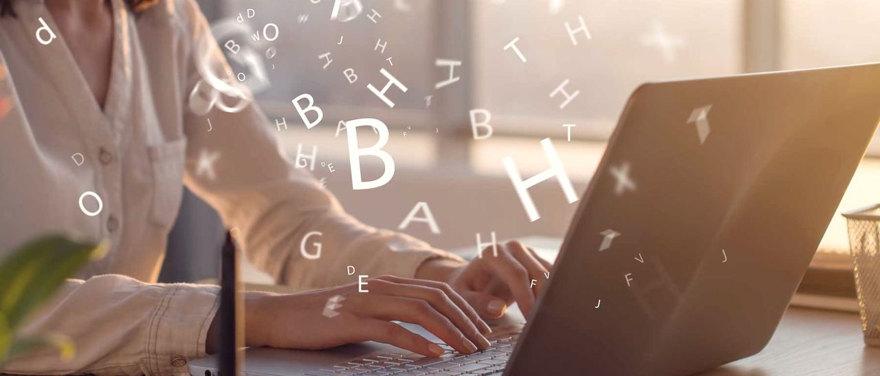 Person tippt auf einem Laptop, Buchstaben schweben über der Tastatur
