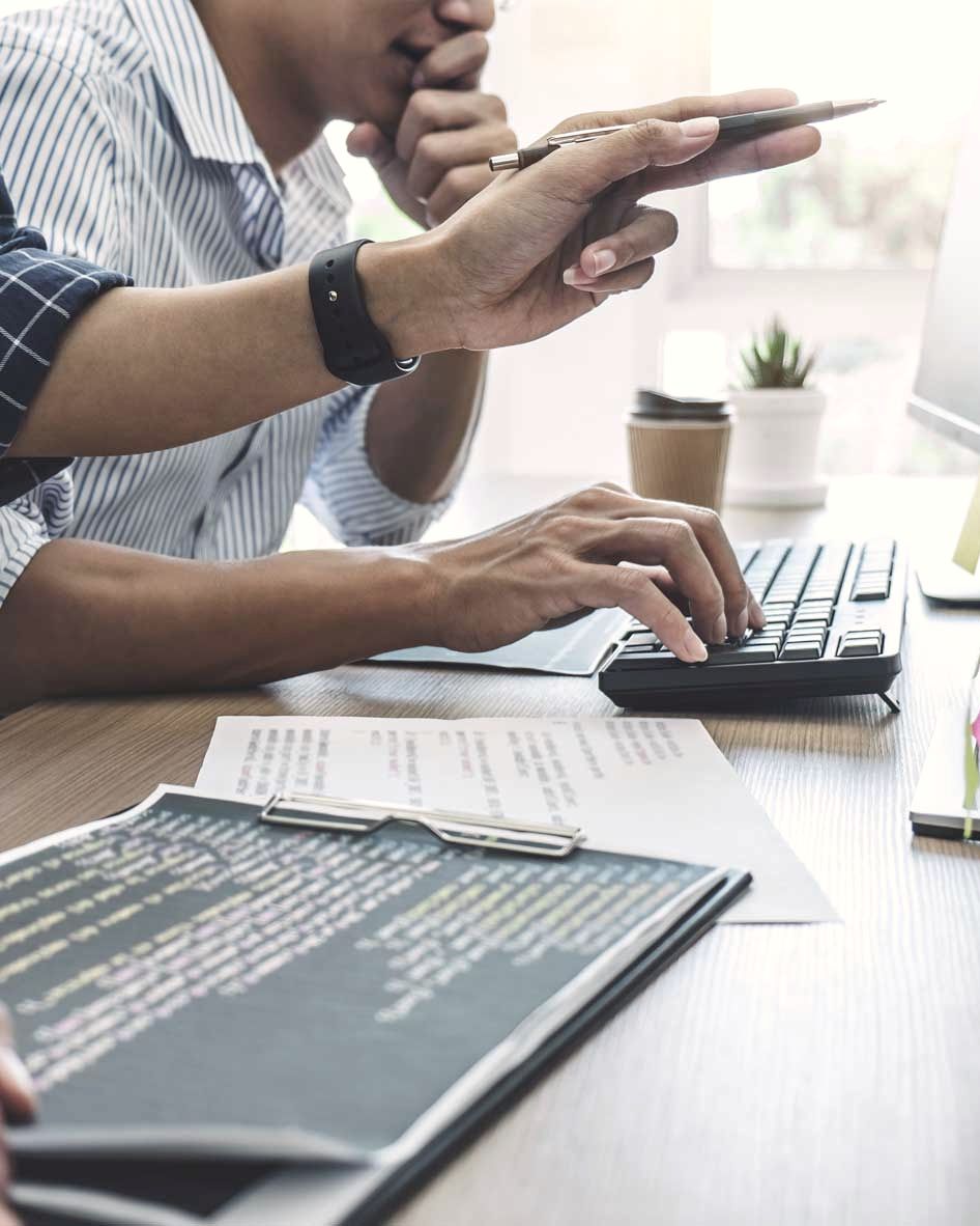 Hände an Tastatur und Notizen bei der Arbeit an einer Website