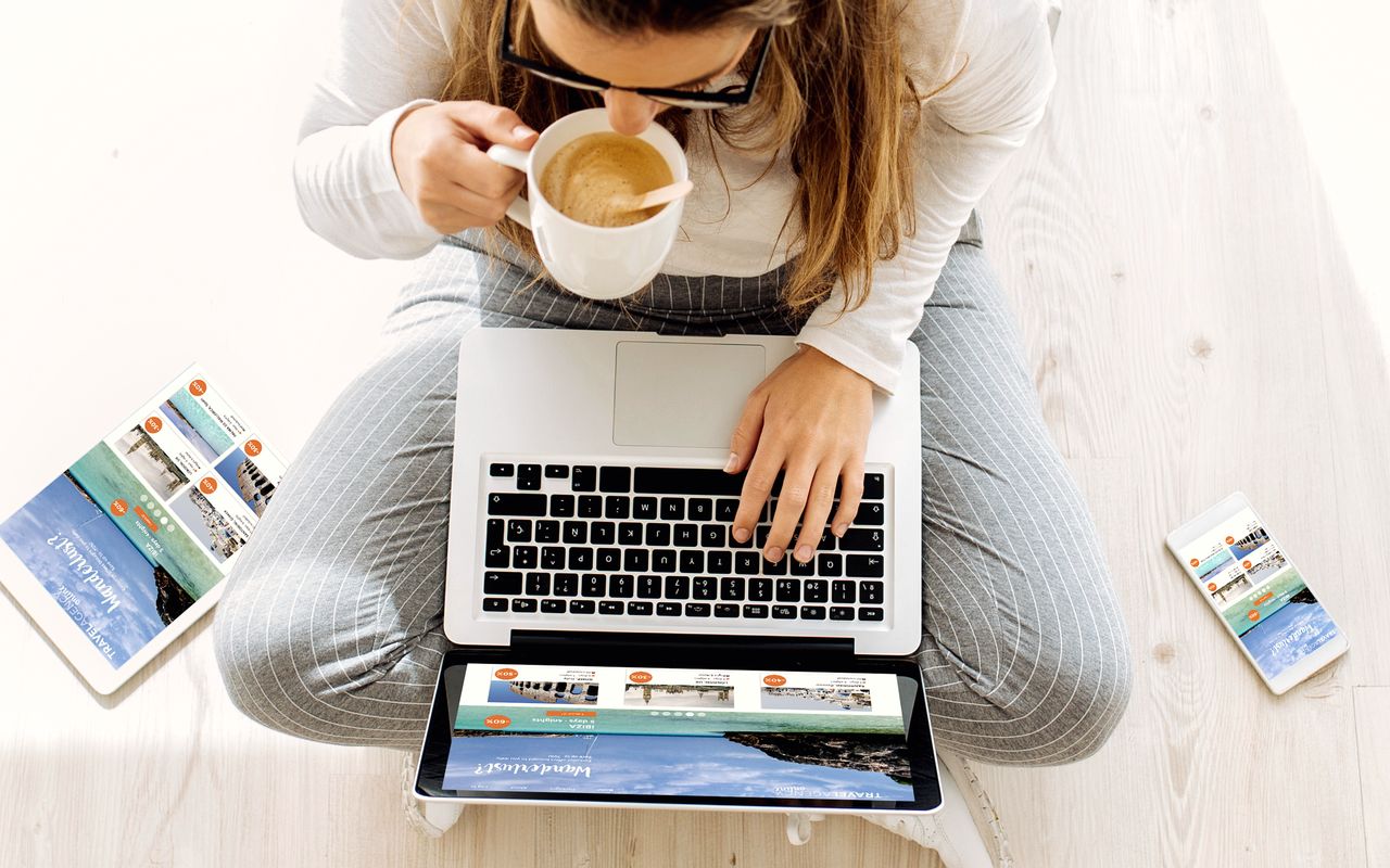 Draufsicht: Person arbeitet am Laptop, daneben Tablet und Smartphone mit derselben responsiven Website